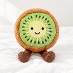 Peluche fruit kawaii kiwi joyeux posée sur un lit blanc, en pleine lumière