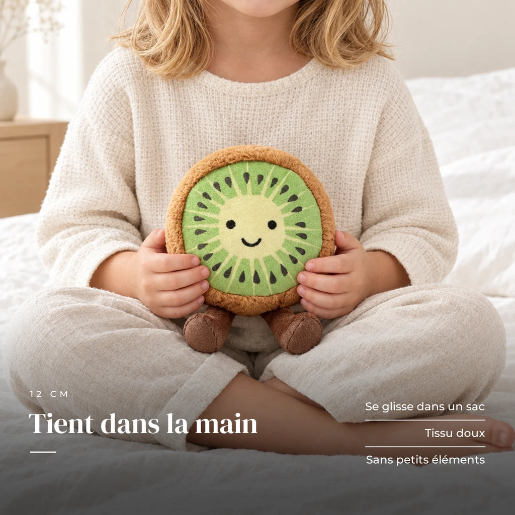 Peluche fruit kawaii kiwi joyeux tenue par un enfant pour montrer sa taille réelle. Tient dans la main : se glisse dans un sac, tissu doux, sans petits éléments