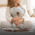 Peluche koala qui respire tenue par un enfant pour montrer sa taille réelle. Taillé pour les câlins : gris ou rose, tissu tout doux, 3 piles AAA