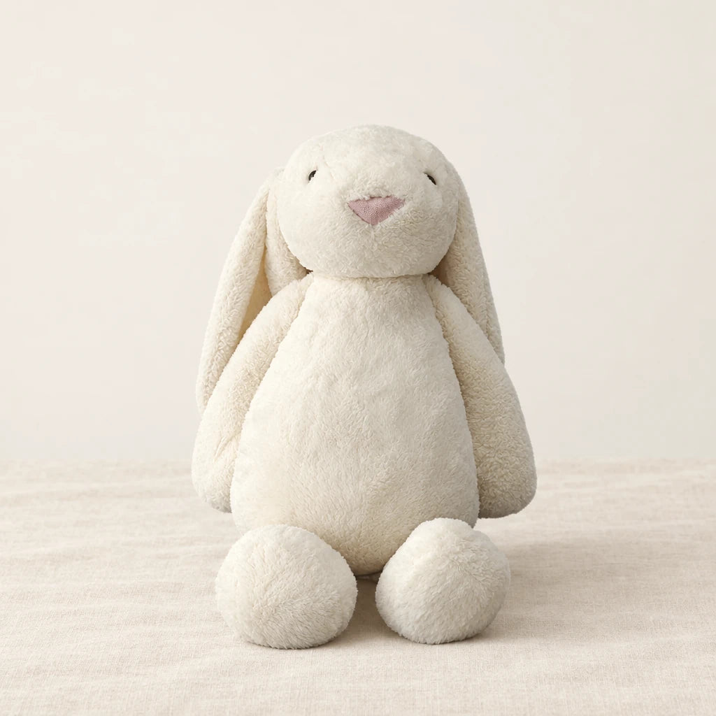 Lapin en peluche moelleux pour bébé blanc sur fond crème, en studio
