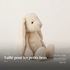 Lapin en peluche moelleux pour bébé sur fond crème, en studio. Taillé pour les petits bras : grandes oreilles, tissu ultra-doux, dès 1 an