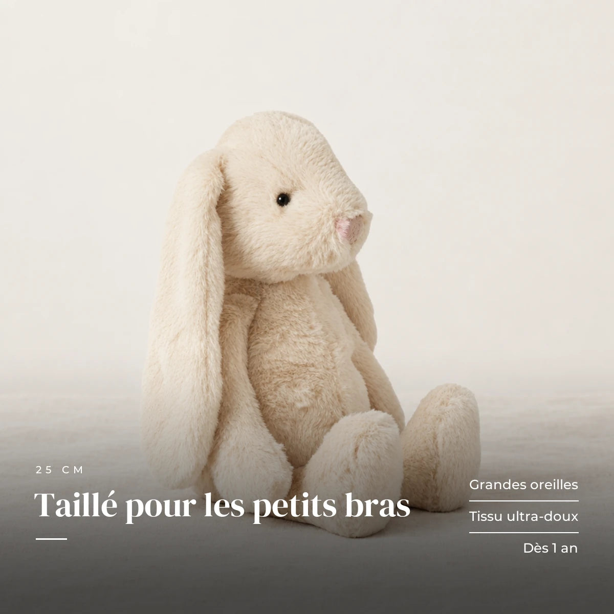 Lapin en peluche moelleux pour bébé sur fond crème, en studio. Taillé pour les petits bras : grandes oreilles, tissu ultra-doux, dès 1 an