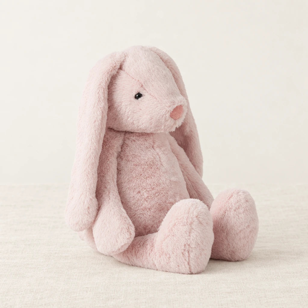 Lapin en peluche moelleux pour bébé rose sur fond crème, en studio