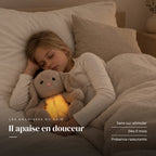 Peluche lapin qui respire serrée par un enfant endormi dans son lit. Il apaise en douceur : sans sur-stimuler, dès 0 mois, présence rassurante