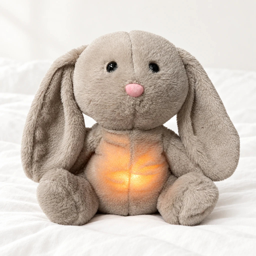 Peluche lapin qui respire posée sur un lit blanc, en pleine lumière