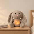 Peluche lapin qui respire posée sur une table de chevet en bois clair