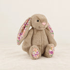 Lapin en peluche avec motif fleuri beige sur fond crème, en studio