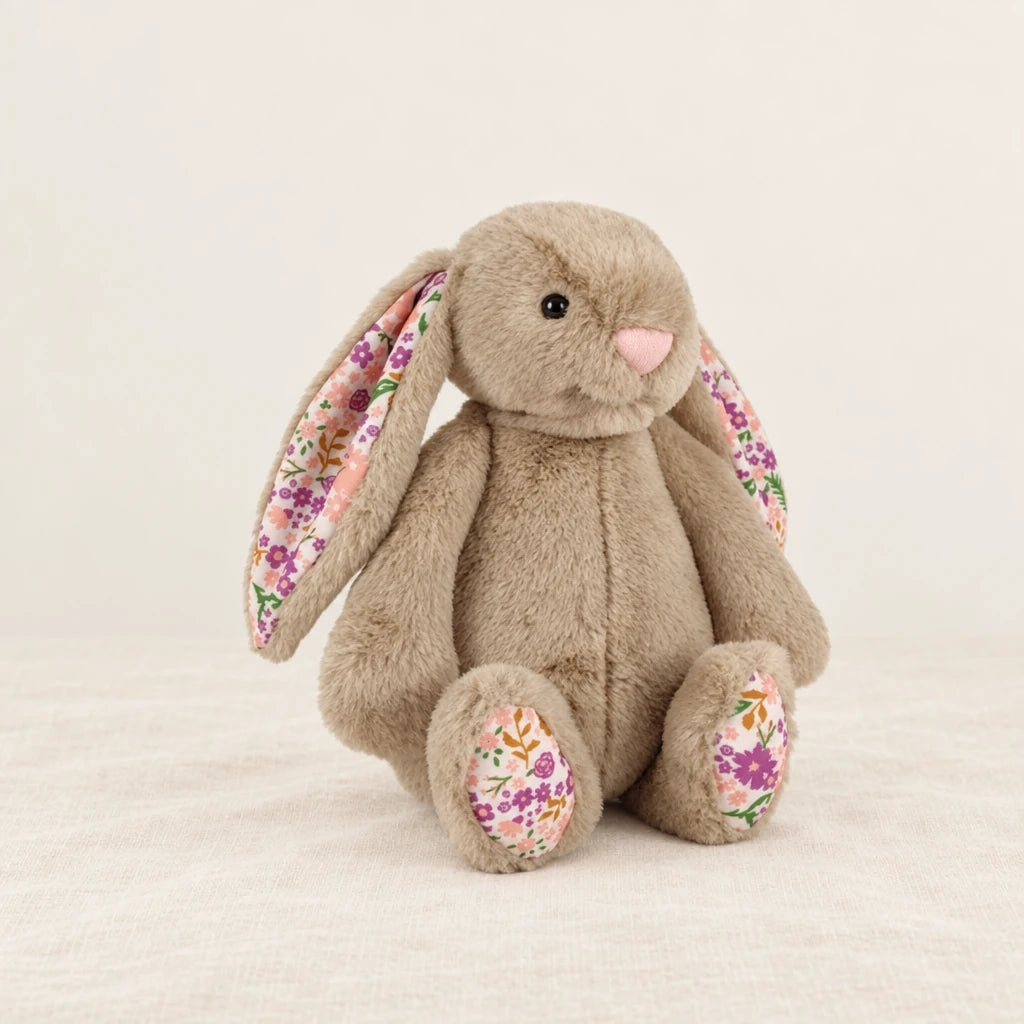 Lapin en peluche avec motif fleuri beige sur fond crème, en studio