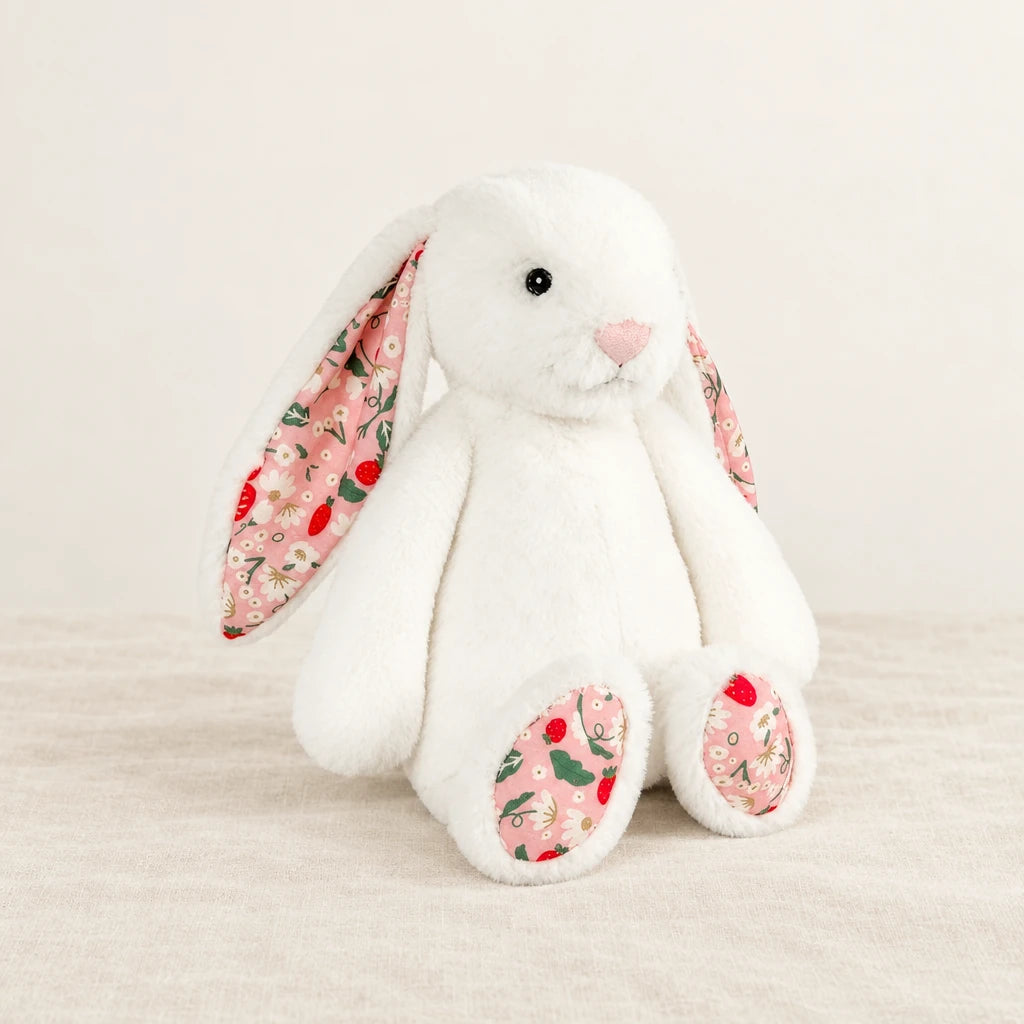 Lapin en peluche avec motif fleuri blanc sur fond crème, en studio