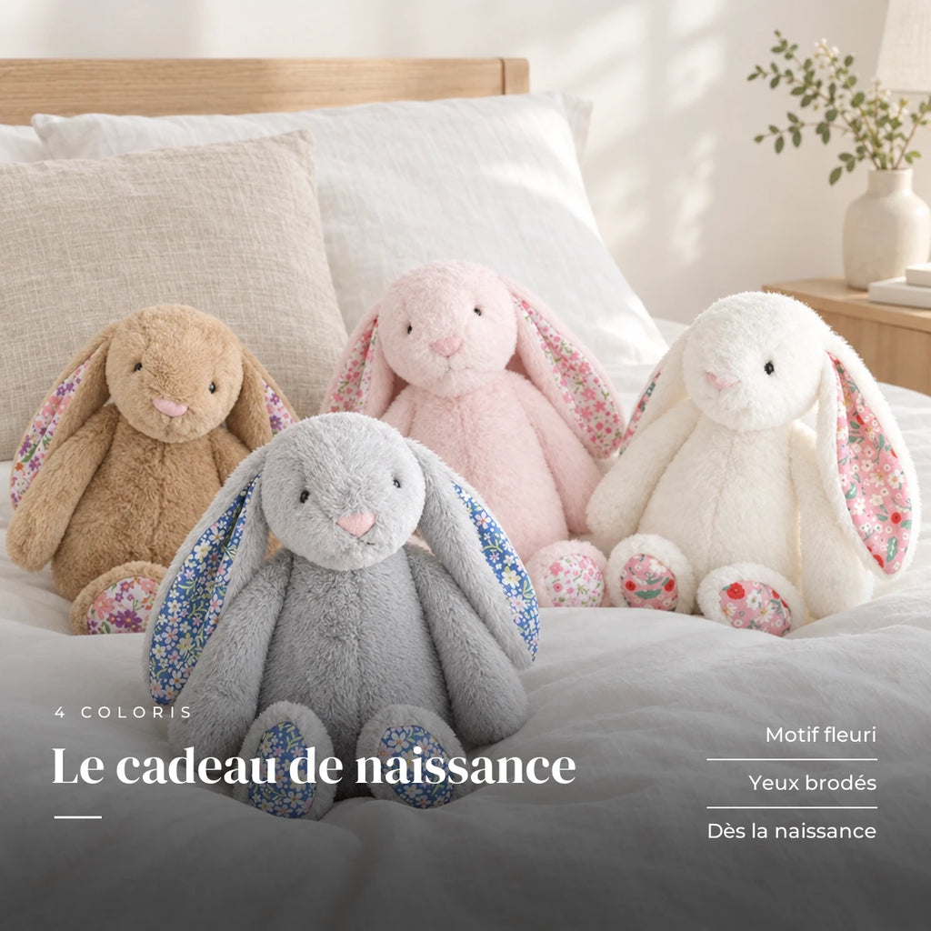 Lapin en peluche avec motif fleuri posé sur un lit en lin blanc. Le cadeau de naissance : motif fleuri, yeux brodés, dès la naissance
