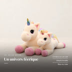 Peluche licorne arc-en-ciel allongée posée sur un lit en lin blanc. Un univers féerique : crinière arc-en-ciel, détails brodés, bleu ou rose