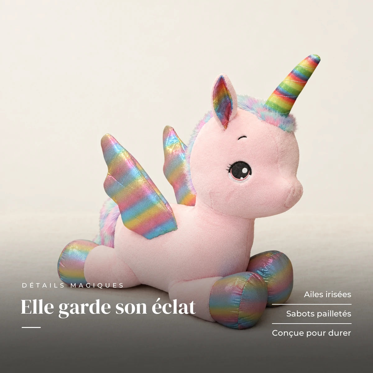 Peluche licorne féerique avec corne et ailes colorées posée sur un lit en lin blanc. Elle garde son éclat : ailes irisées, sabots pailletés, conçue pour durer