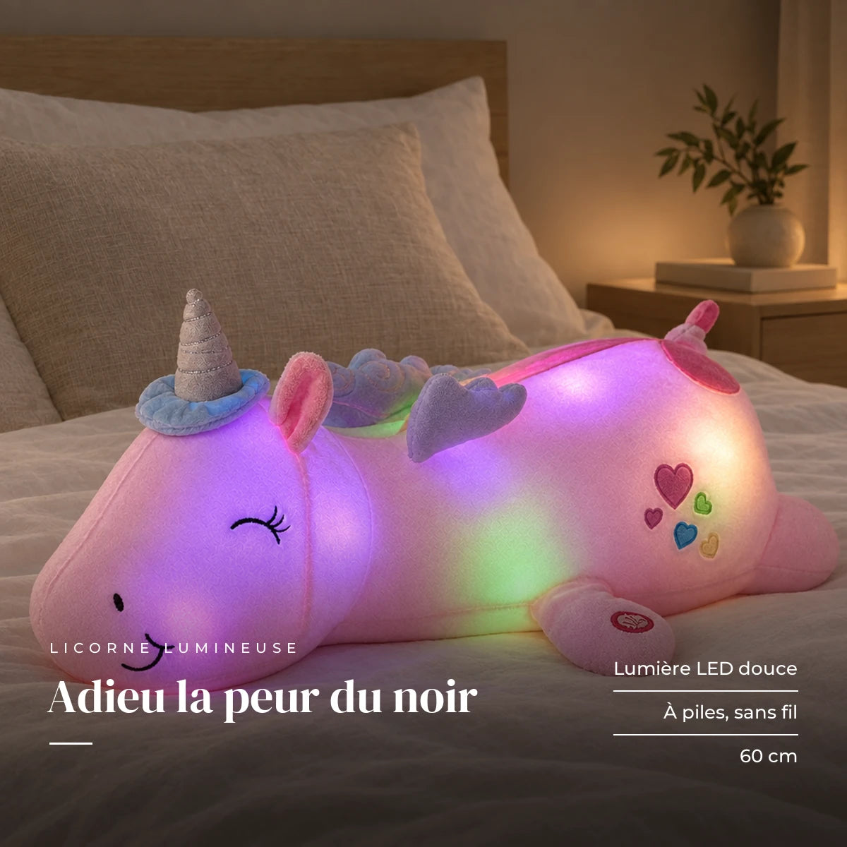 Peluche licorne rose veilleuse lumineuse et magique posée sur un lit en lin blanc. Adieu la peur du noir : lumière LED douce, à piles, sans fil, 60 cm