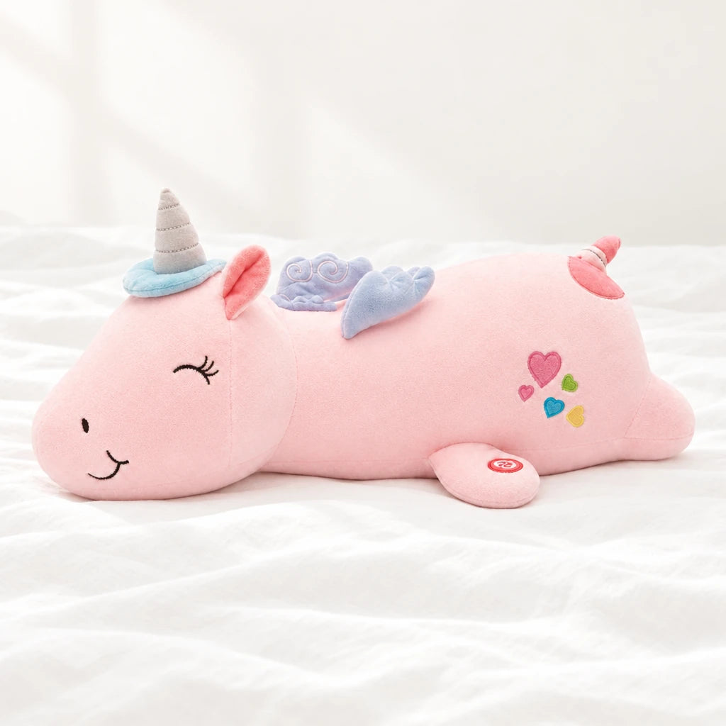 Peluche licorne rose veilleuse lumineuse et magique posée sur un lit blanc, en pleine lumière