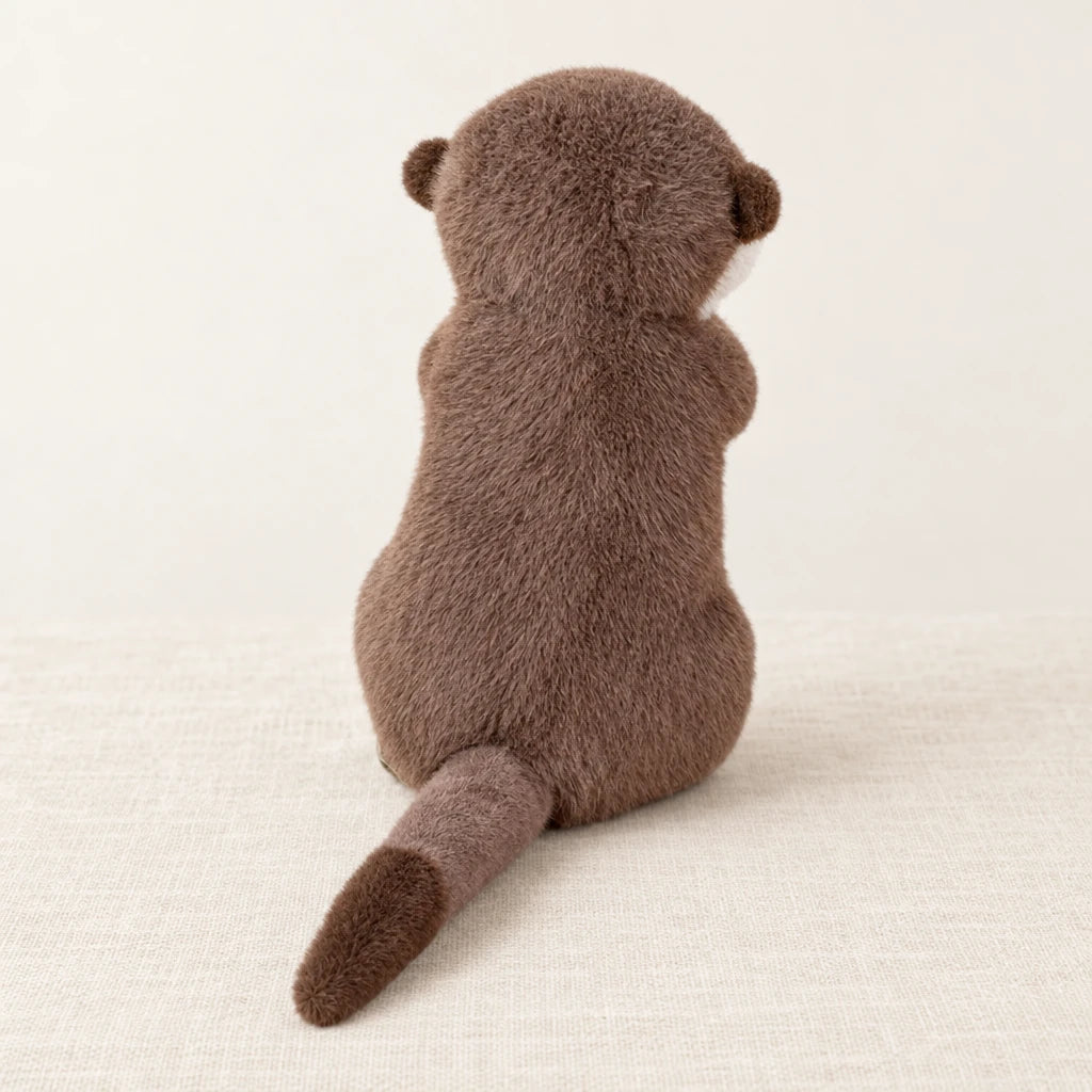 Loutre en peluche attendrissante vue de dos sur fond crème