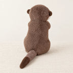 Loutre en peluche attendrissante vue de dos sur fond crème
