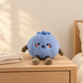 Peluche fruit kawaii myrtille attendrissante posée sur une table de chevet en bois clair