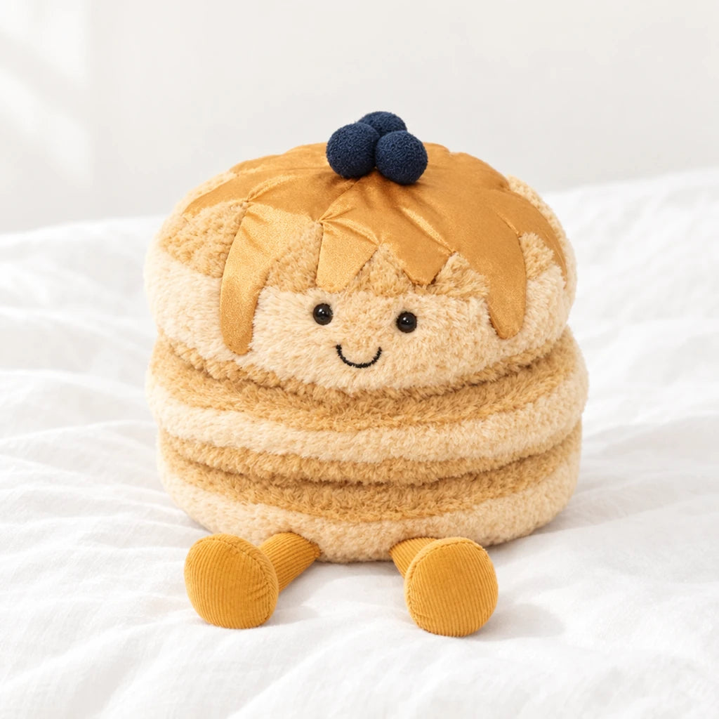 Peluche petit dej’ pancakes kawaii posée sur un lit blanc, en pleine lumière