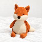 Peluche renard assis tout doux posée sur un lit blanc, en pleine lumière