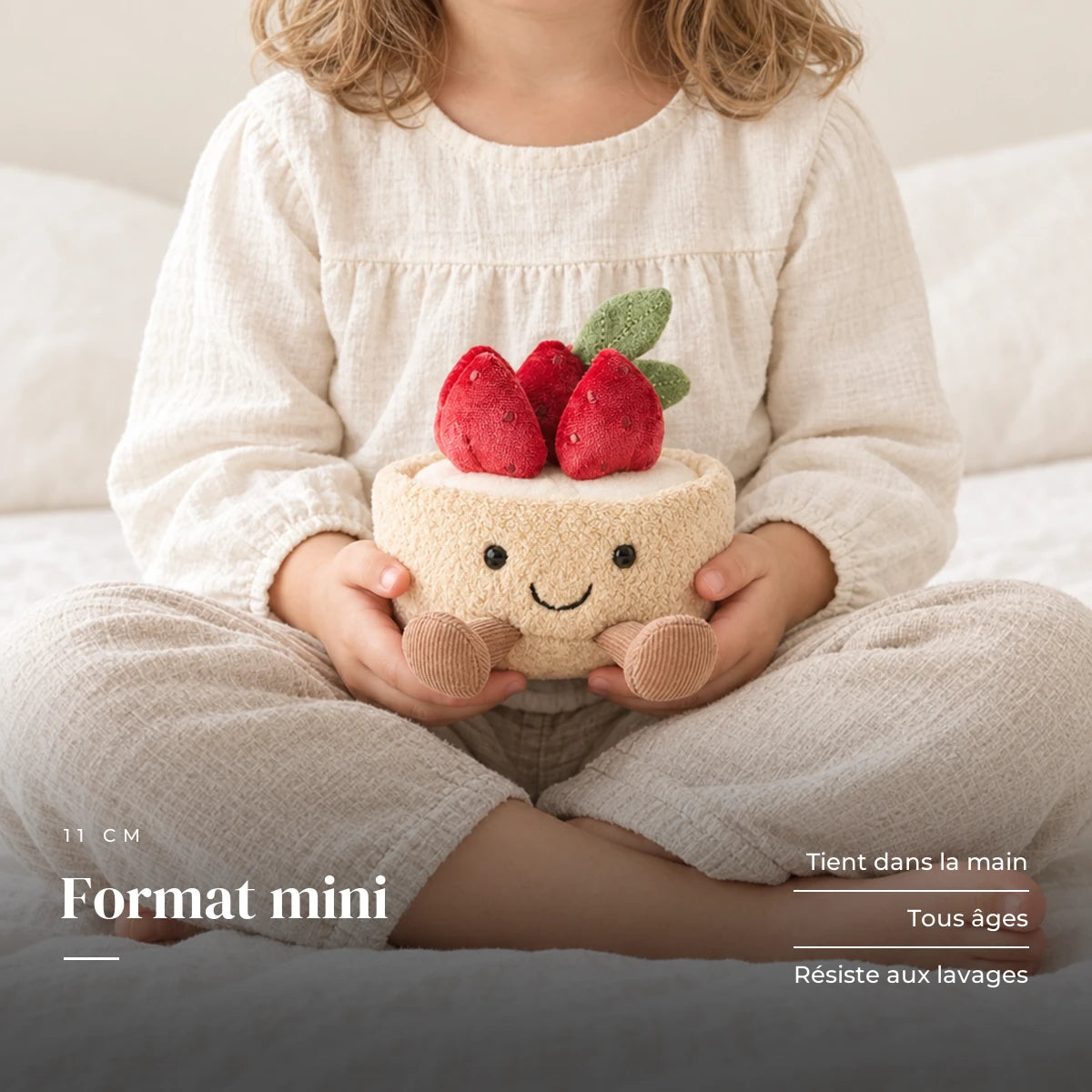 Peluche tarte fraise gourmande kawaii tenue par un enfant pour montrer sa taille réelle. Format mini : tient dans la main, tous âges, résiste aux lavages