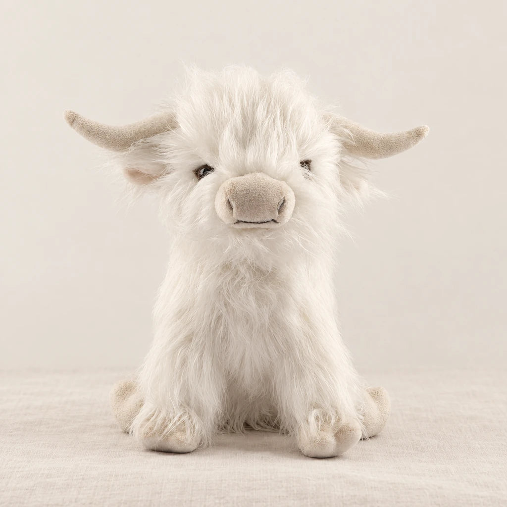 Peluche vache Highland à poils longs blanche sur fond crème, en studio