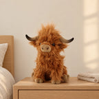 Peluche vache Highland à poils longs marron posée sur une table de chevet en bois clair