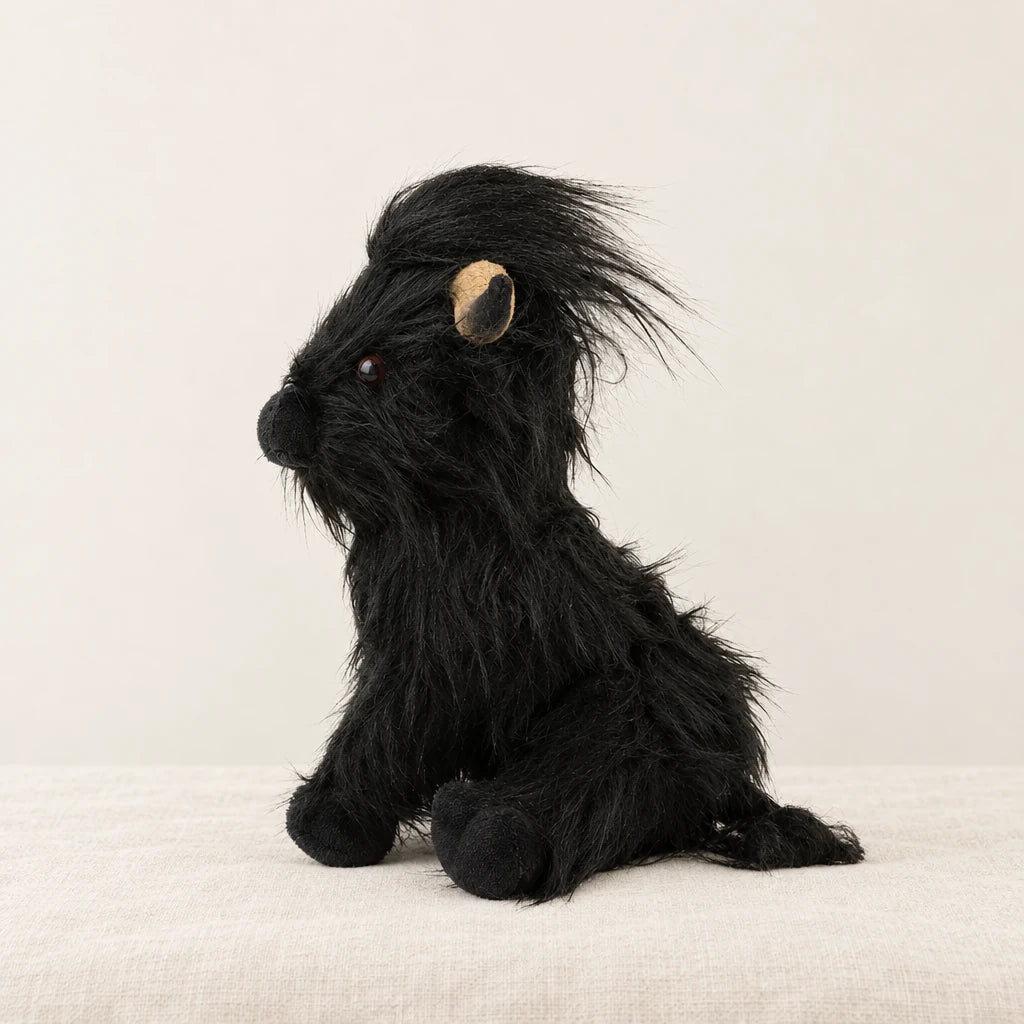 Peluche vache Highland à poils longs noire sur fond crème, en studio