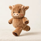 Peluche vache originale qui court marron sur fond crème, en studio
