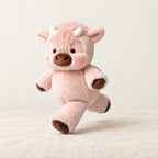 Peluche vache originale qui court rose sur fond crème, en studio