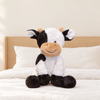 Peluche vache au sourire doux posée sur un lit en lin blanc
