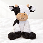 Peluche vache au sourire doux posée sur un lit blanc, en pleine lumière