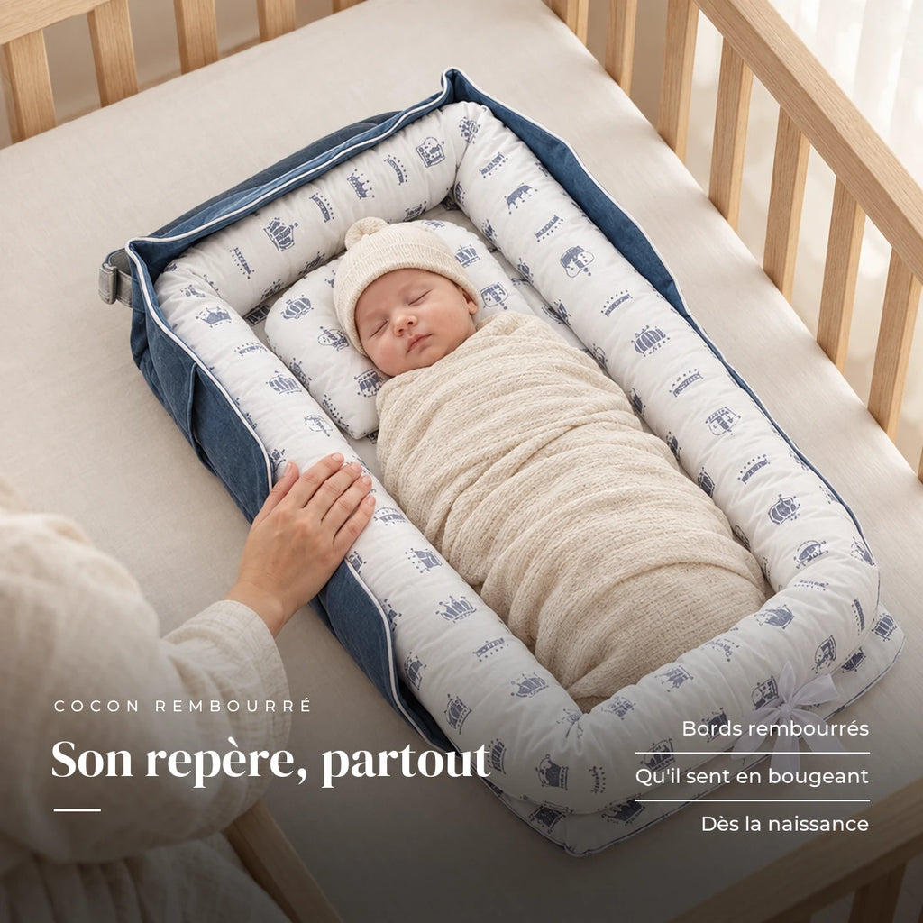 Nouveau-né emmailloté au repos sur le dos, la main d’un parent sur le bord : Réducteur de lit - Cocon Nomade