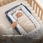 Nouveau-né emmailloté au repos sur le dos, la main d’un parent sur le bord : Réducteur de lit - Cocon Nomade