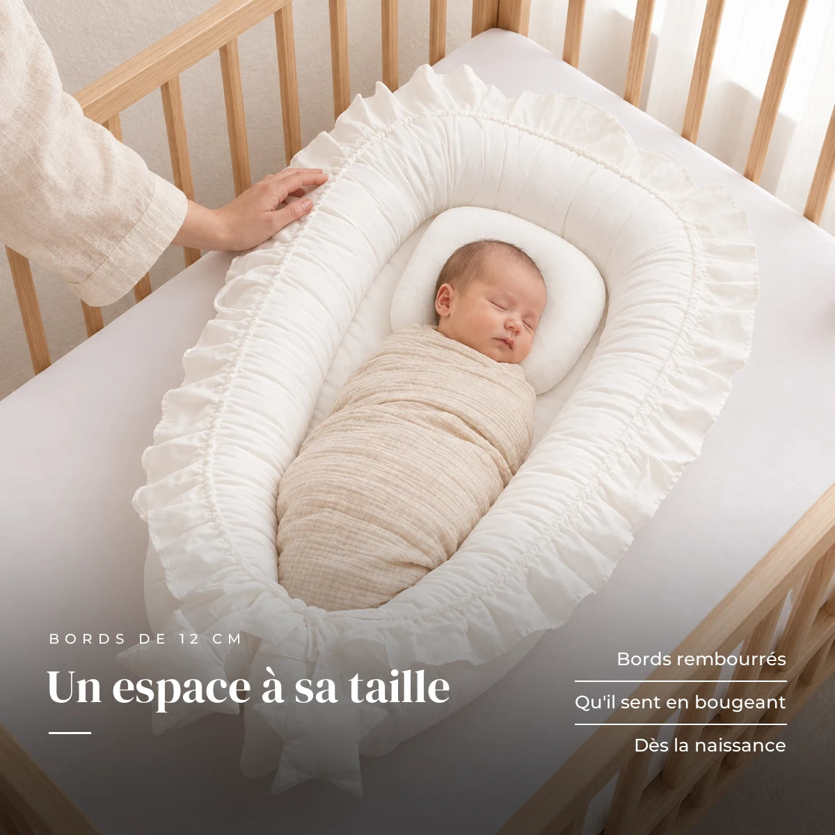 Nouveau-né emmailloté au repos sur le dos, la main d’un parent sur le bord : Réducteur de lit - Cocoon
