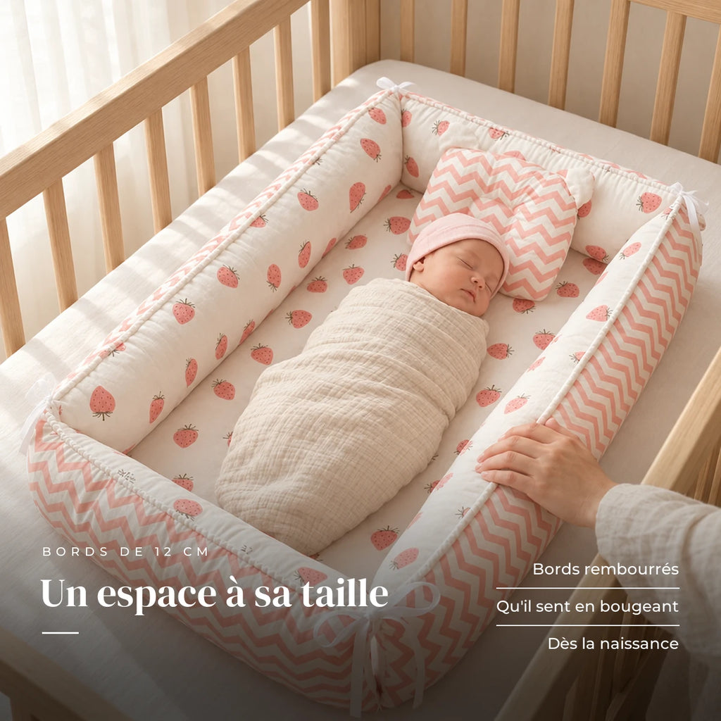Nouveau-né emmailloté au repos sur le dos, la main d’un parent sur le bord : Réducteur de lit - Cozy