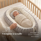 Nouveau-né emmailloté au repos sur le dos, la main d’un parent sur le bord : Réducteur de lit - DreamNest