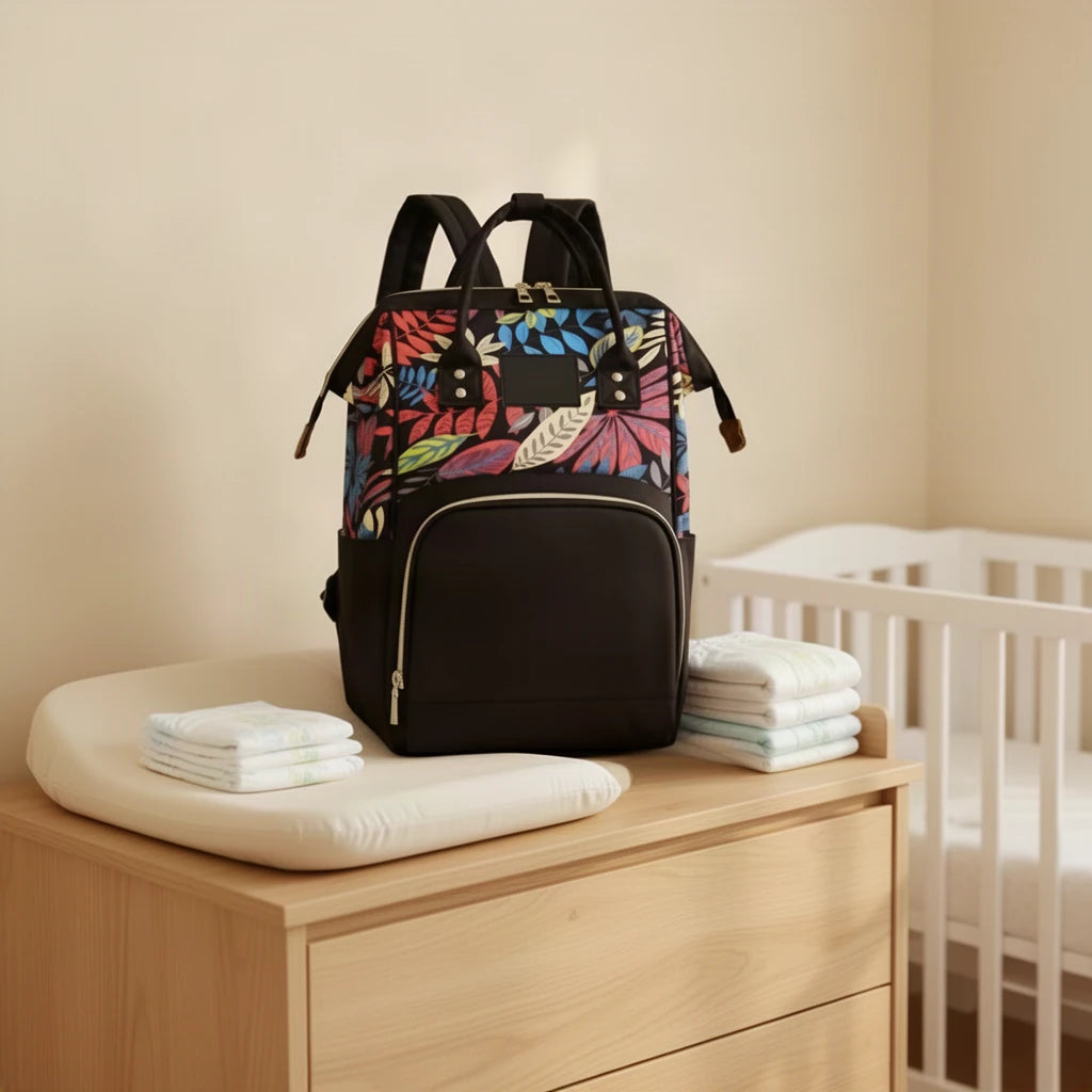 Sac à dos à langer bicolore imprimé feuillage posé sur une commode à langer
