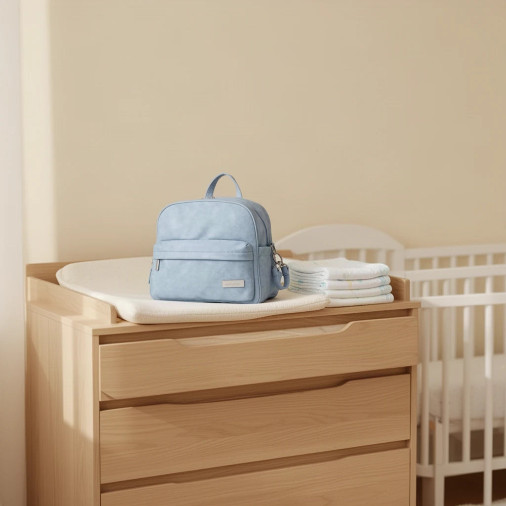 Sac à dos à langer compact effet cuir posé sur une commode à langer