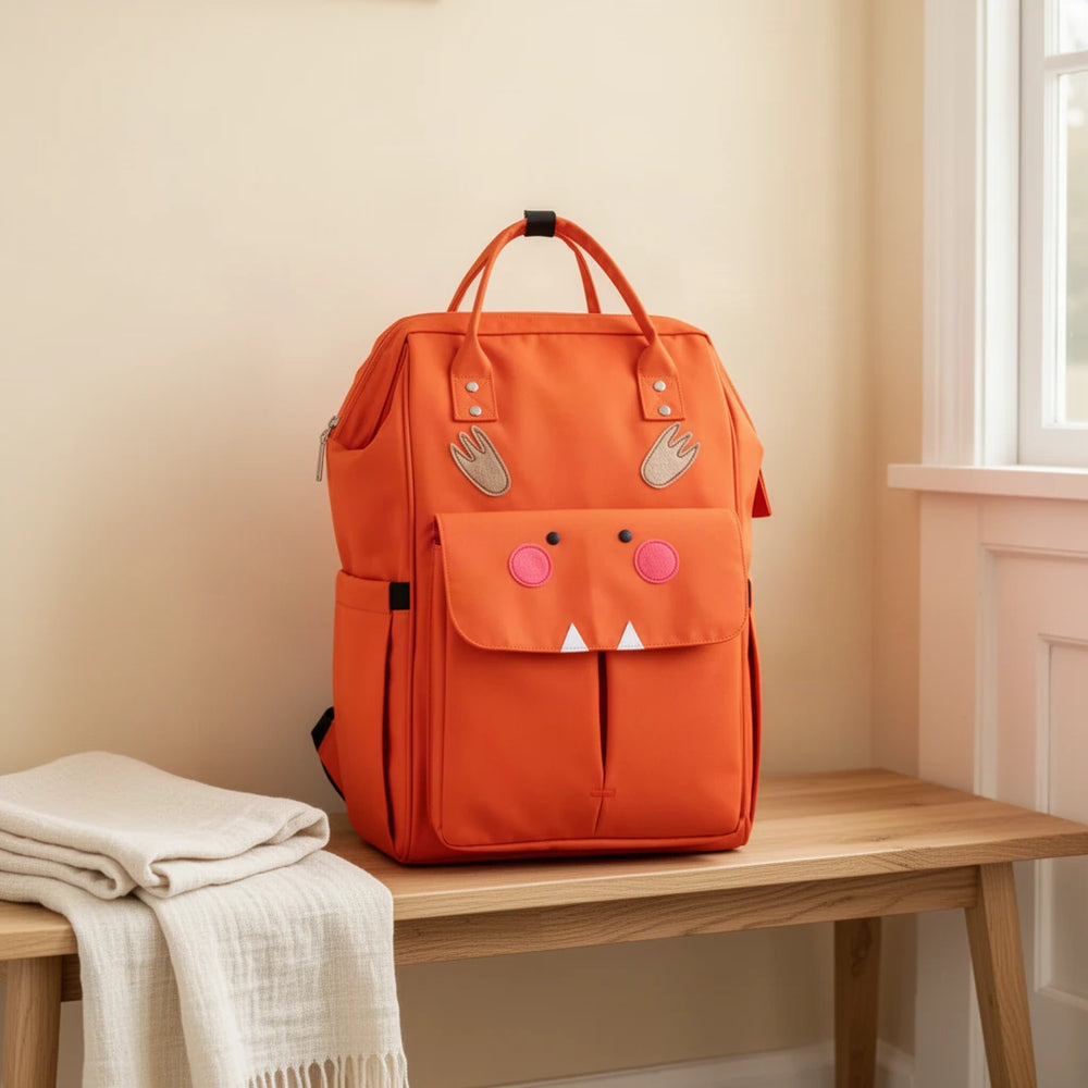 Sac à dos à langer motifs animaux avec attaches poussette posé sur un banc dans une entrée