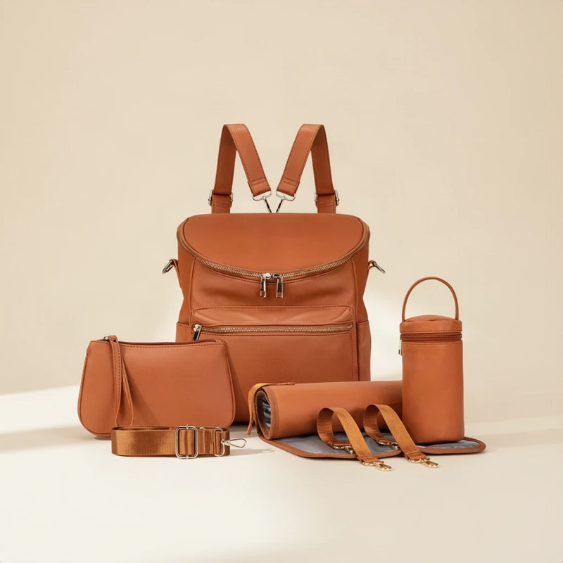 Sac à dos à langer simili cuir camel avec accessoires sur fond clair
