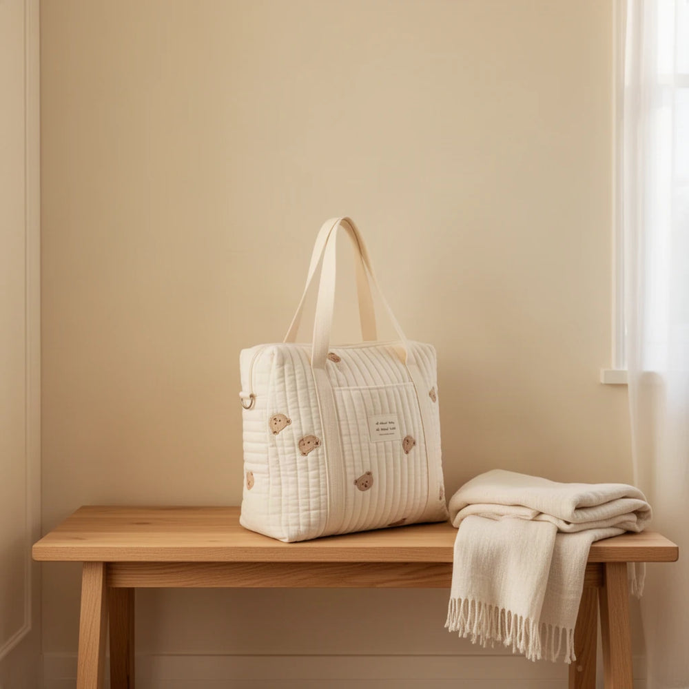 Sac à langer cabas en coton matelassé brodé posé sur un banc dans une entrée