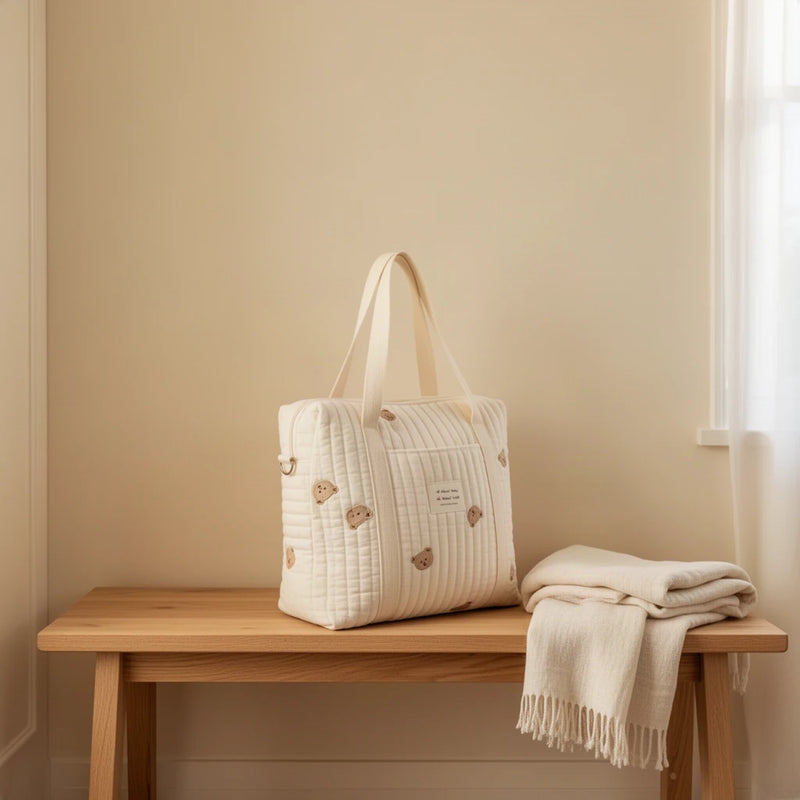 Sac à langer cabas en coton matelassé brodé posé sur un banc dans une entrée