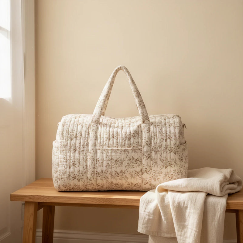 Sac à langer matelassé à fleurs, format week-end posé sur un banc dans une entrée