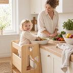 Enfant debout dans la tour d’apprentissage qui aide à cuisiner à côté de sa maman
