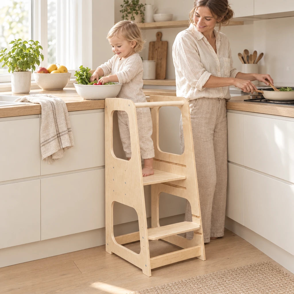 Enfant debout dans la tour d’observation bébé qui aide à cuisiner à côté de sa maman