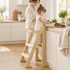 Enfant debout dans la tour d’observation pliable qui aide à cuisiner à côté de sa maman