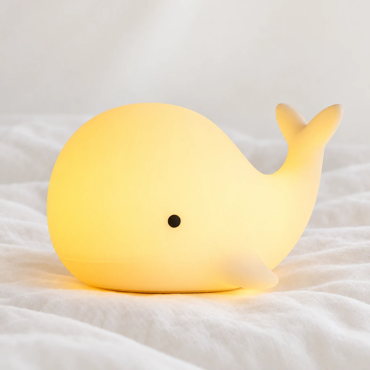 Veilleuse baleine bébé en silicone en gros plan sur un drap blanc