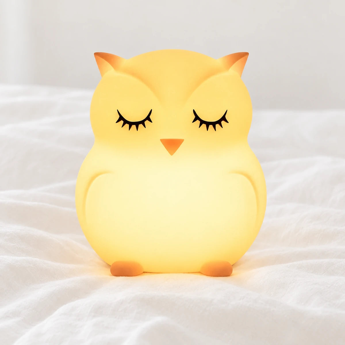 Veilleuse hibou bébé en silicone en gros plan sur un drap blanc