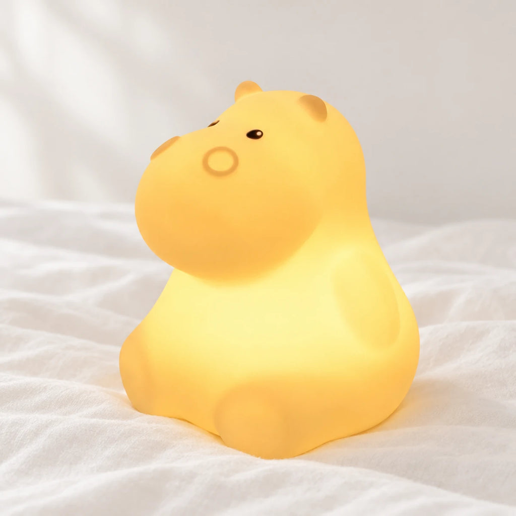 Veilleuse hippopotame avec télécommande en gros plan sur un drap blanc