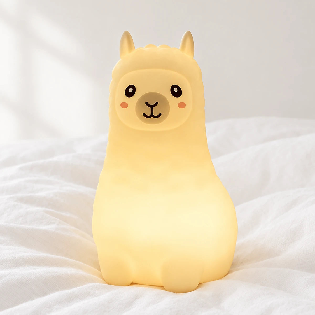 Veilleuse lama bébé rechargeable en silicone en gros plan sur un drap blanc